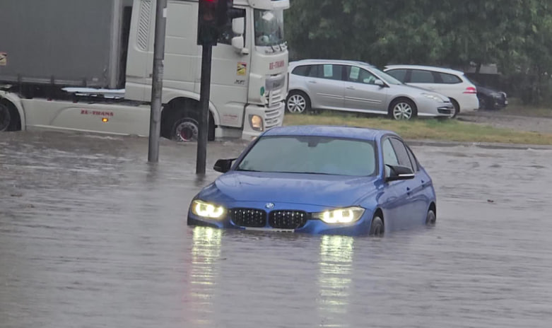 Синяя машина марки BMW стоит в воде из-за дождя